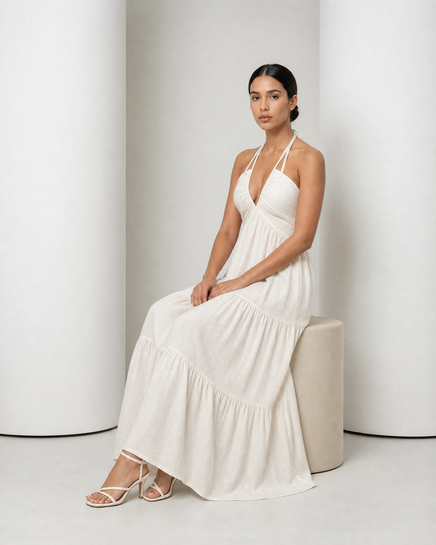 Model seated in the cream Alva dress, the tiered skirt falling over her knees