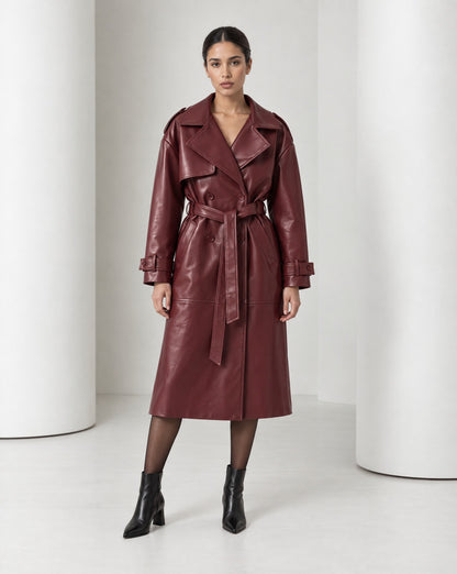 Model in the Alya vegan leather trench in burgundy, belted at the waist and falling to mid-calf