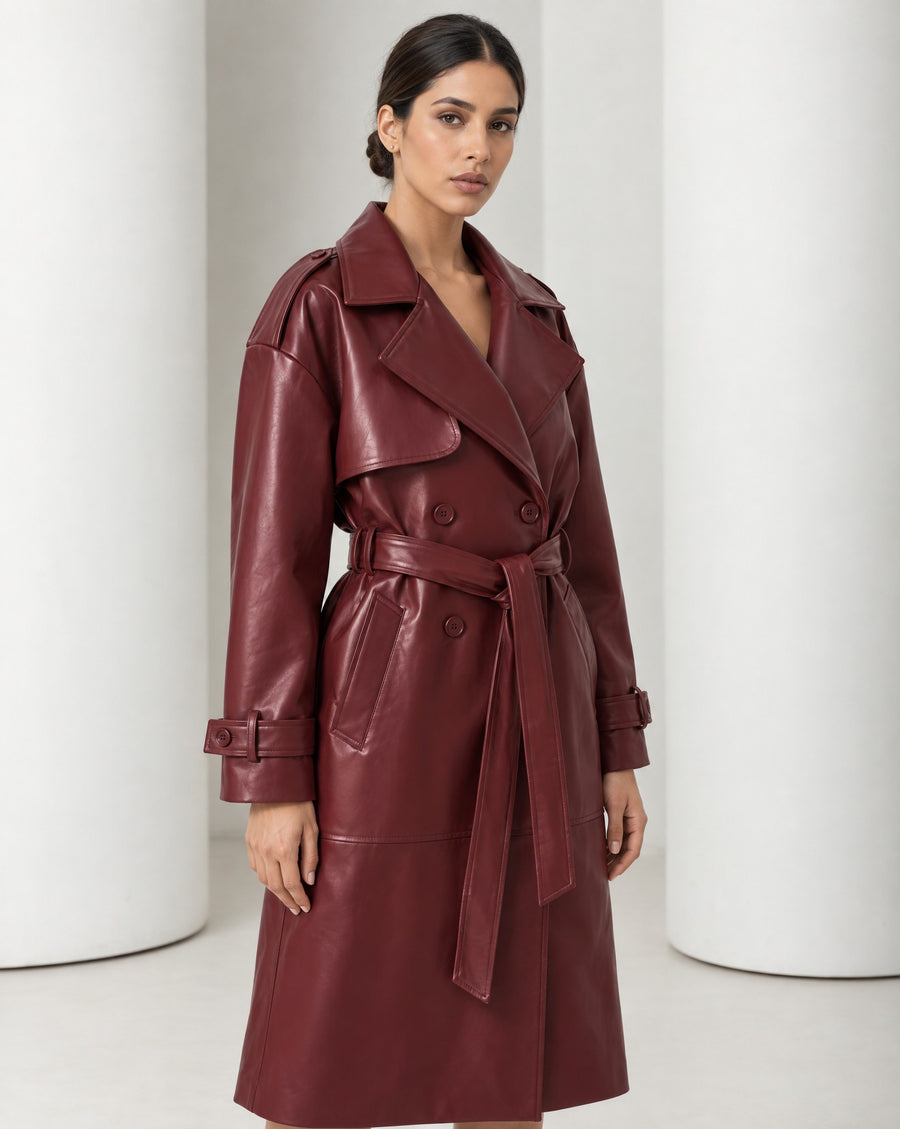 Model in the Alya vegan leather trench in burgundy, belted at the waist and falling to mid-calf