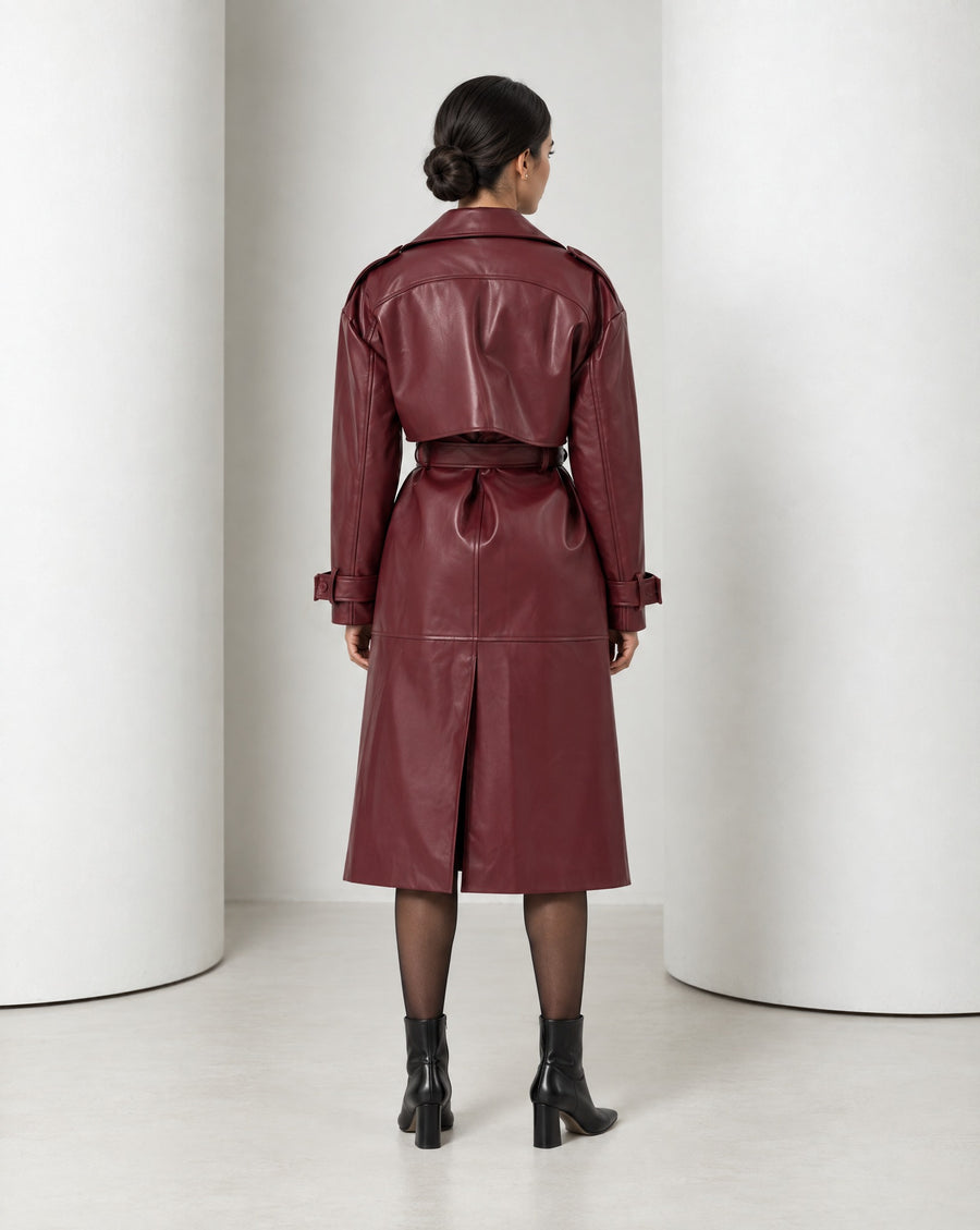 Model in the Alya vegan leather trench in burgundy, belted at the waist and falling to mid-calf