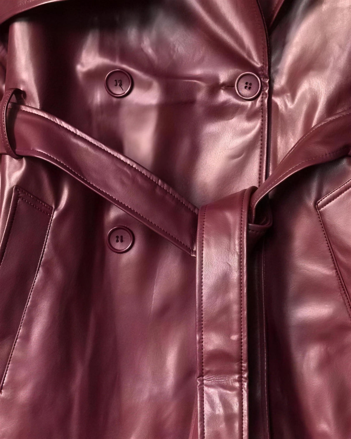 Close view of the Alya trench front, matching burgundy buttons, knotted tie belt and slanted pocket