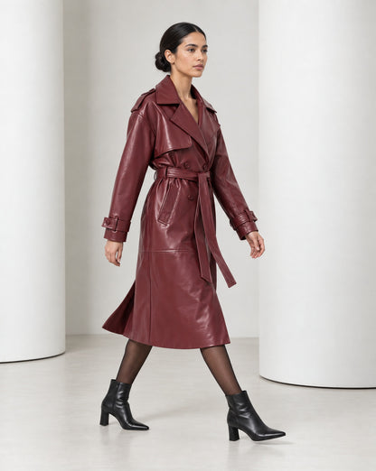 Side view of the Alya burgundy vegan leather trench mid-stride, the long skirt moving with the step