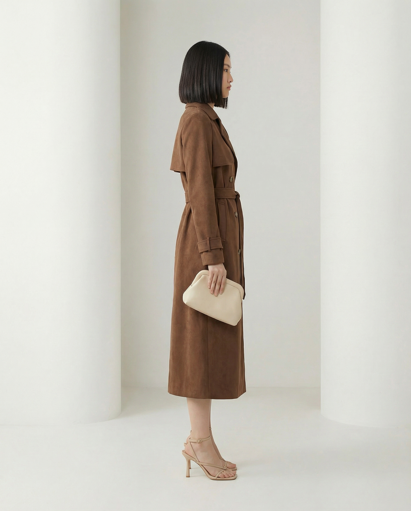 Alya suede trench shown from the side, storm flap and buckled cuff straps, hem at mid-calf