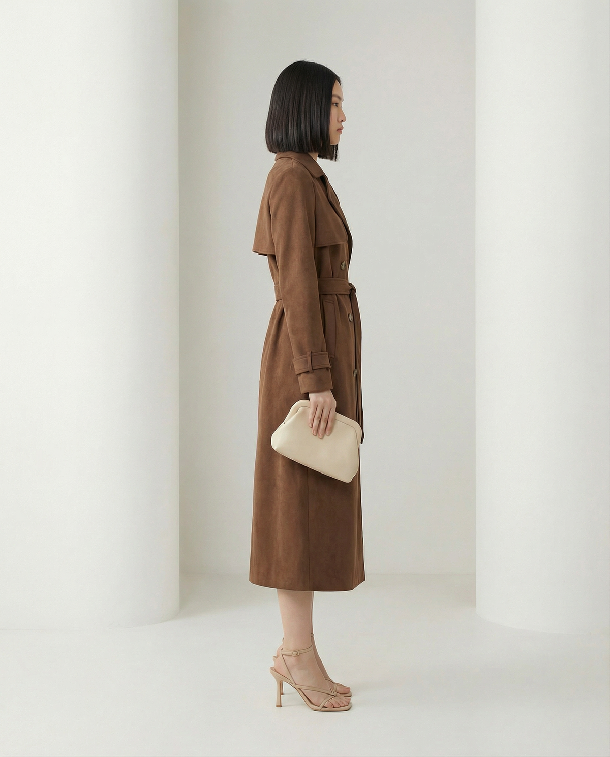 Alya suede trench shown from the side, storm flap and buckled cuff straps, hem at mid-calf