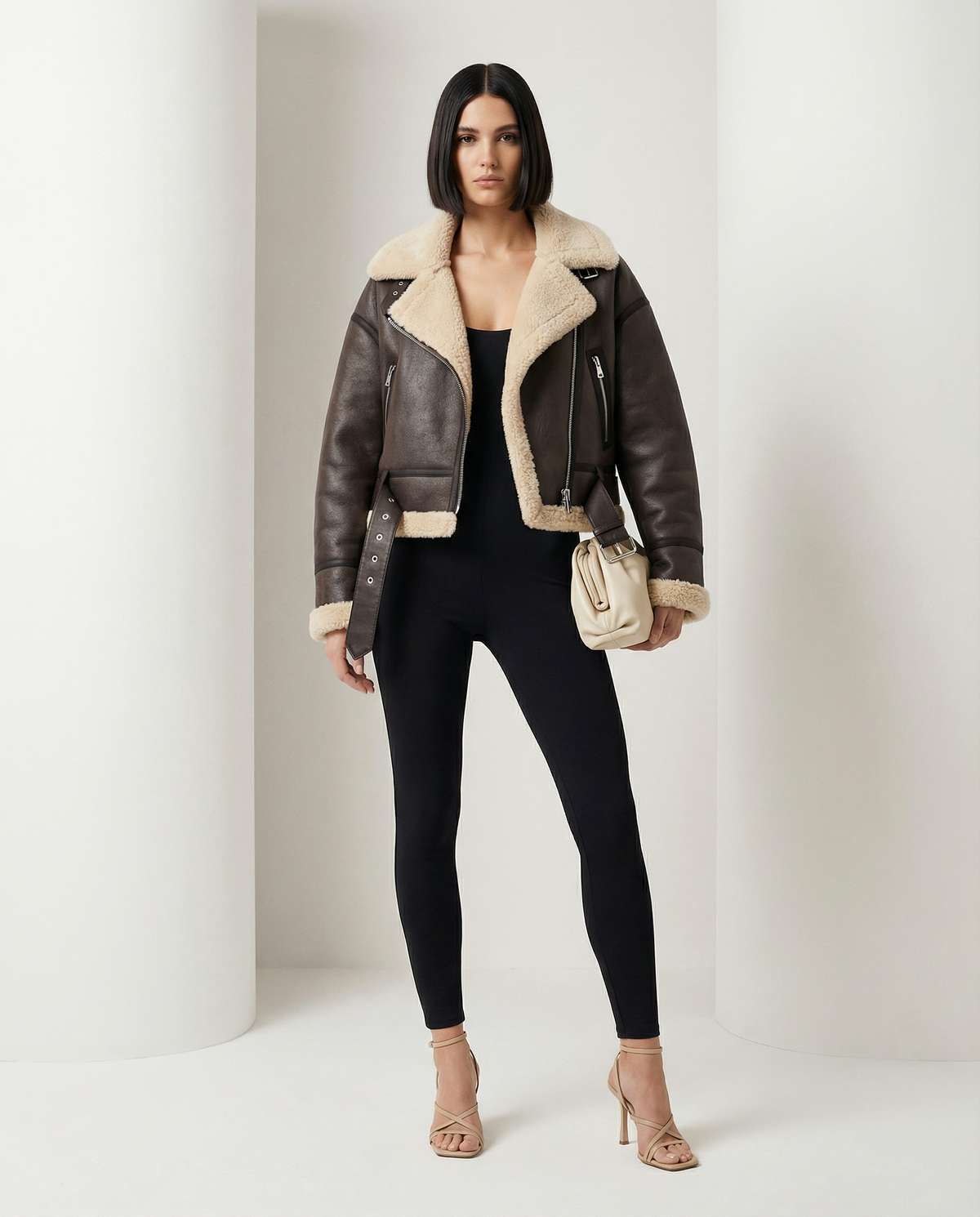 Brown aviator jacket with cream shearling trim and a buckled waist strap, three-quarter view