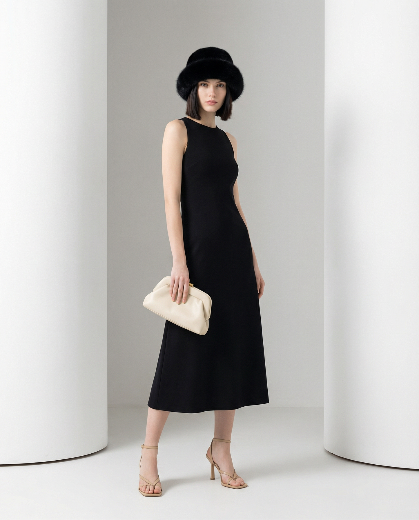 Black fuzzy faux-fur hat with a sleeveless black midi dress, full-length three-quarter view