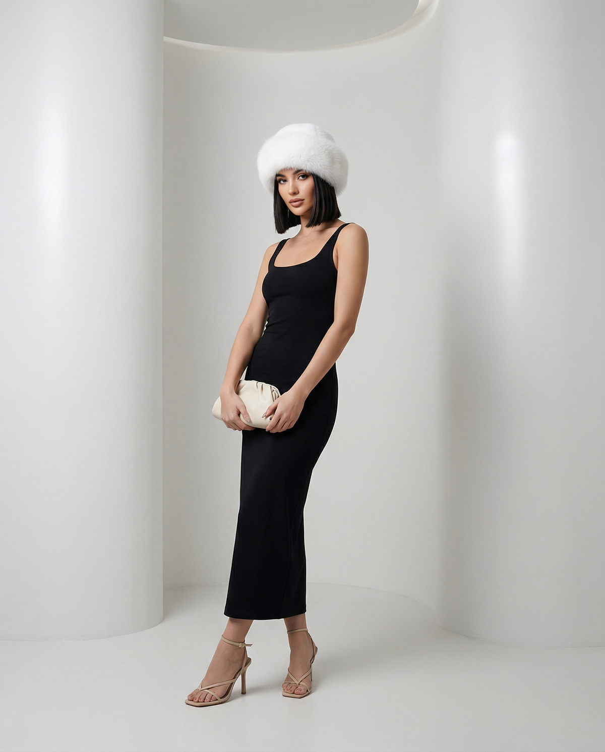 Bright white fuzzy faux-fur hat worn with a black tank midi dress, full-length standing pose