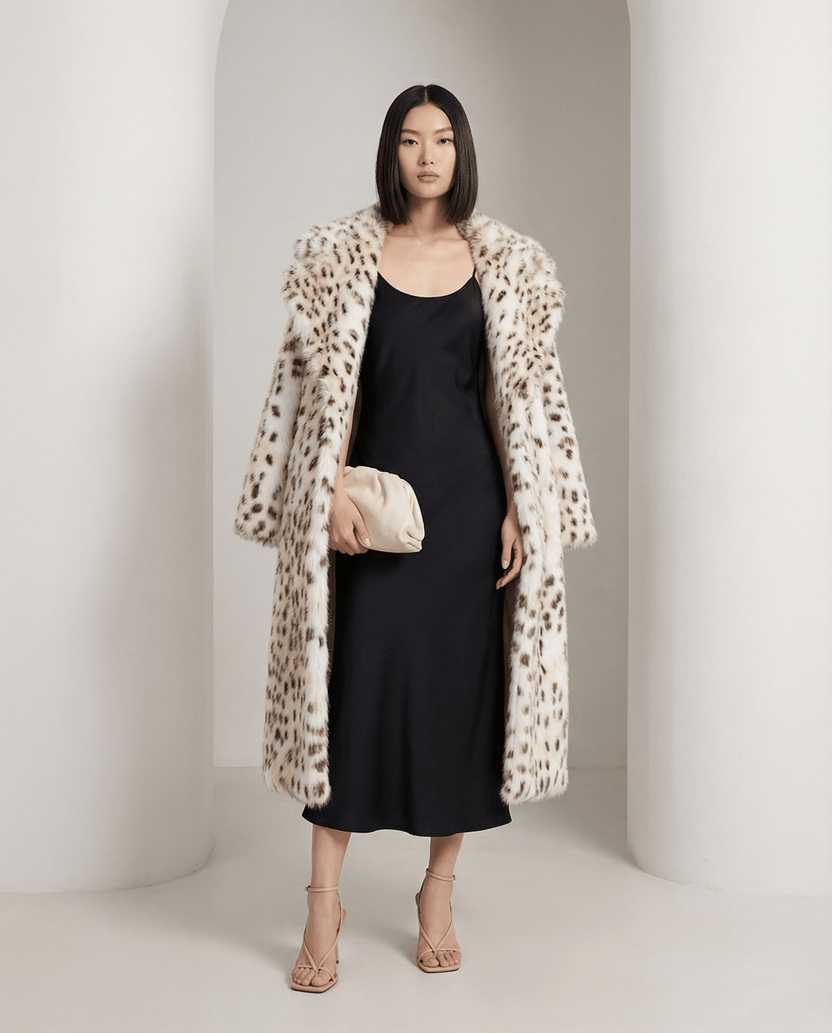 Asteria Snow-Leopard Faux-Fur Coat over a black slip dress, wide collar turned out, full length
