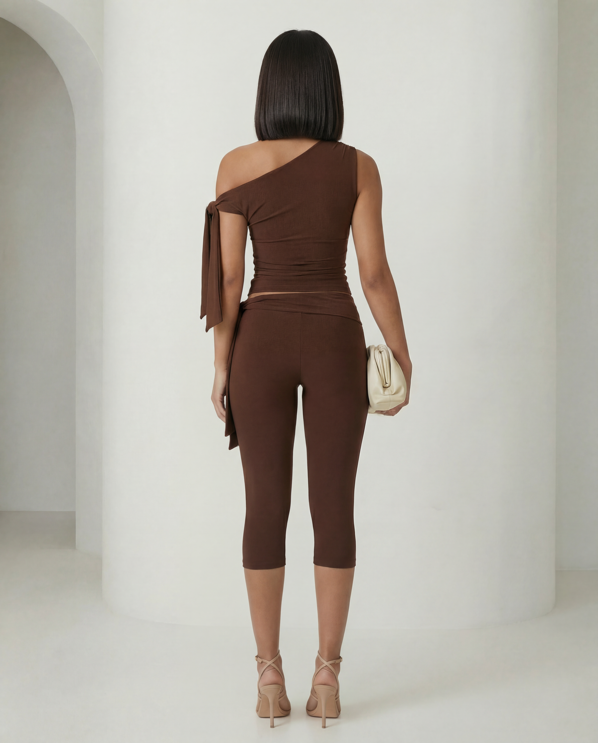 Back view of the bitter chocolate asymmetric set showing the ruched top and capri hem at the calf
