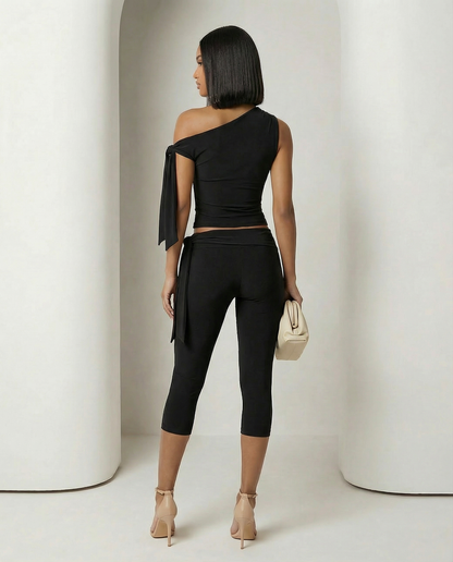 Back view of the black asymmetric set showing the trailing tie and calf-length capri leggings