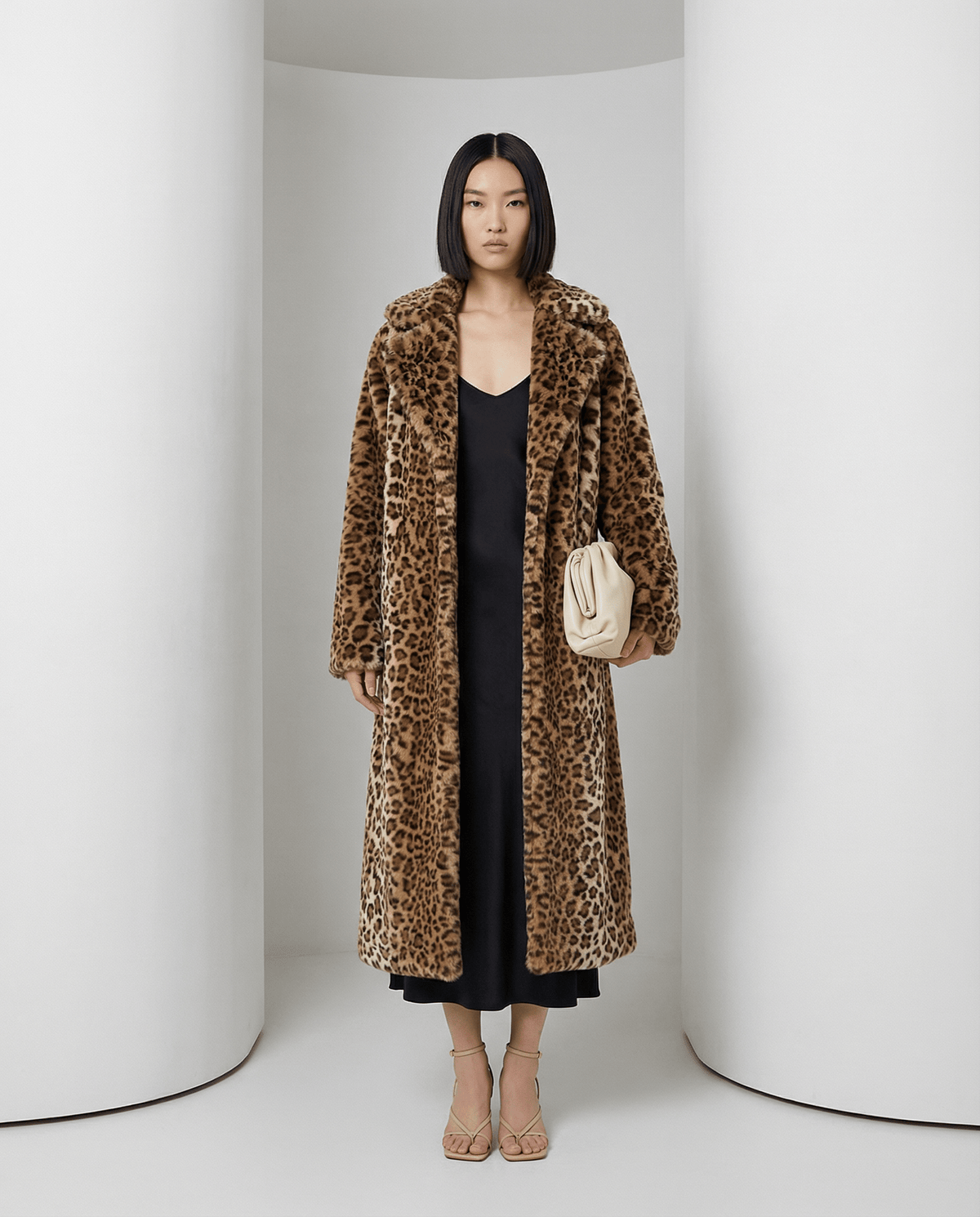 Cocoa leopard Aurelia coat open over a black slip dress with a cream clutch, full length