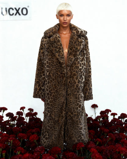 Leopard faux-fur coat worn open with a deep neckline, standing in dark red carnations