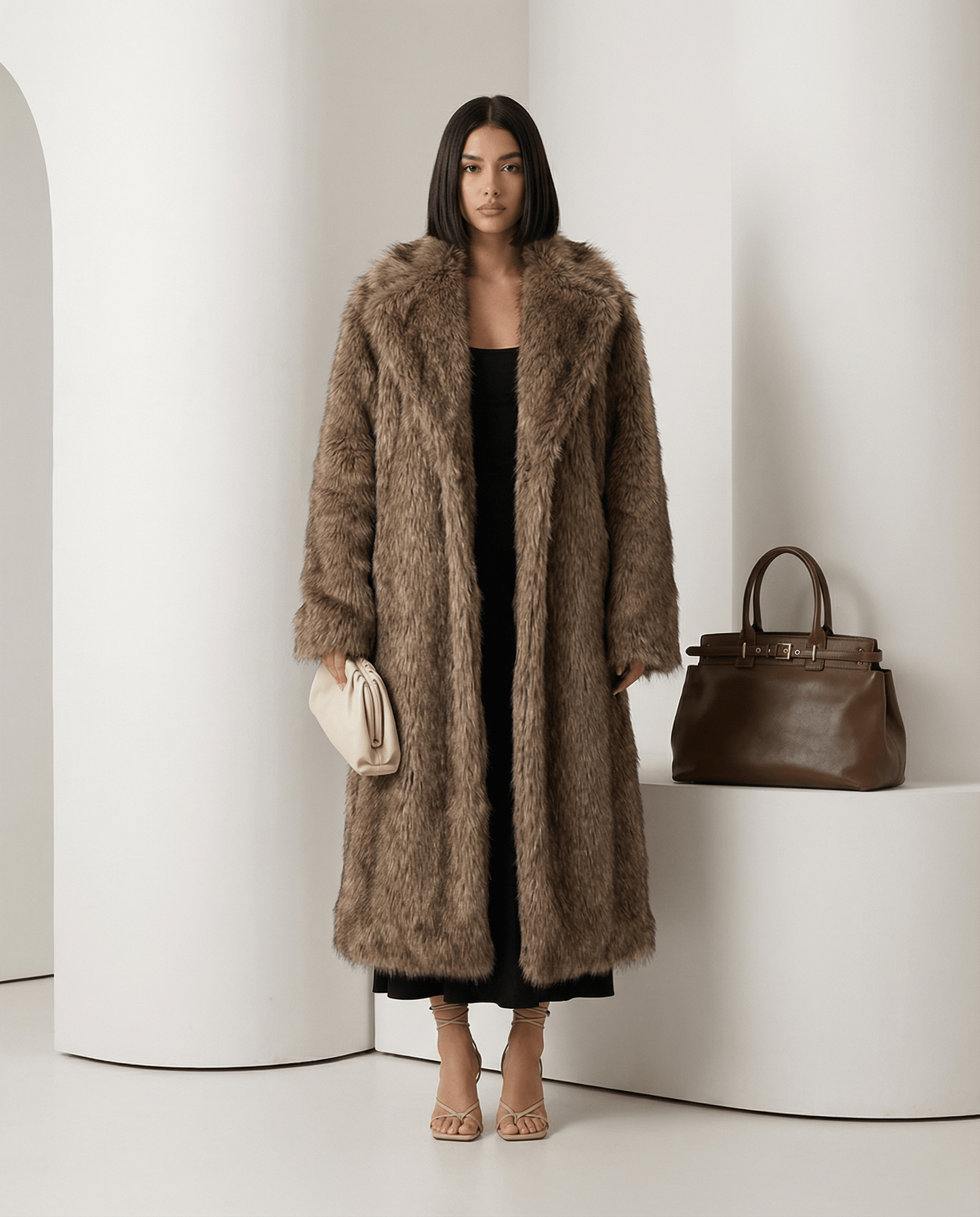 Beige Eden longline faux-fur coat worn open over a black dress, full length beside a tan handbag