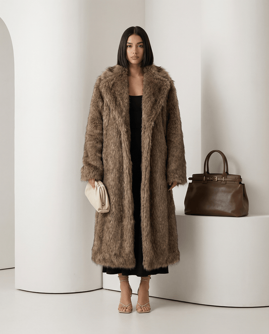 Beige Eden longline faux-fur coat worn open over a black dress, full length beside a tan handbag