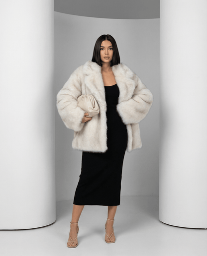 Frosted white Elara oversized faux-fur coat worn open over a black midi dress, full length