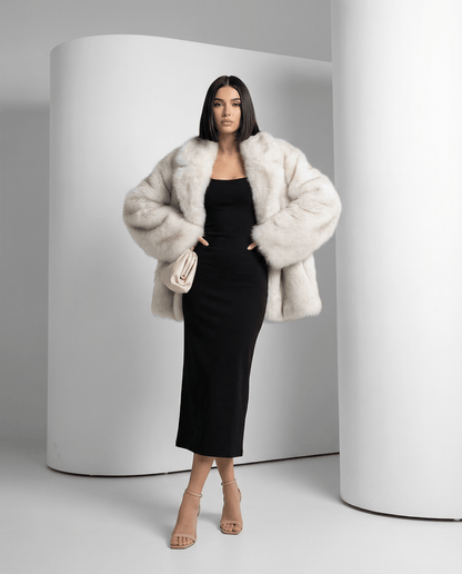 Frosted white faux-fur coat with hands in pockets, showing the oversized shoulder and sleeve