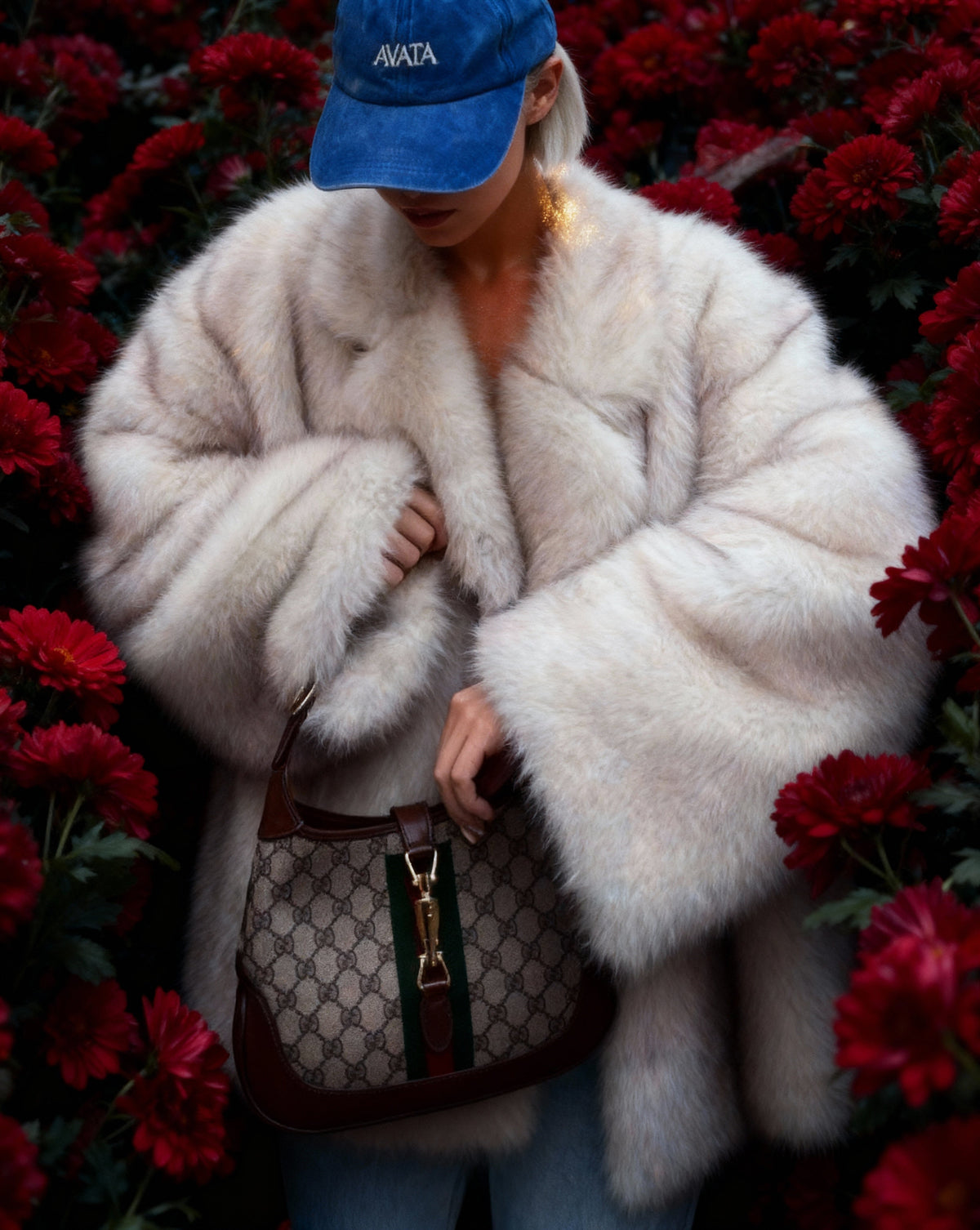 Close crop of the frosted white faux-fur coat and its dense plush pile, worn among red flowers