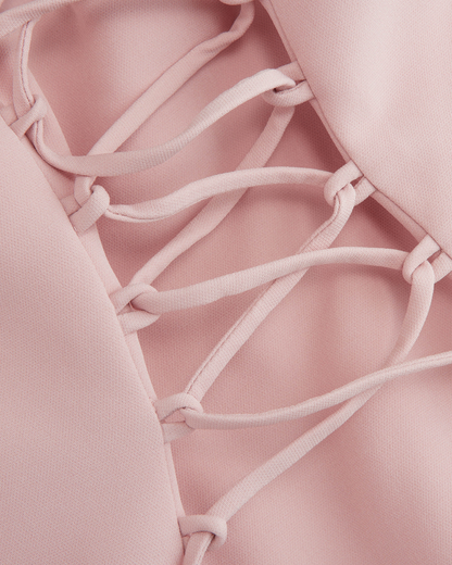 Close view of the Embla corset lacing, blush cord threaded through knotted fabric loops, no hardware