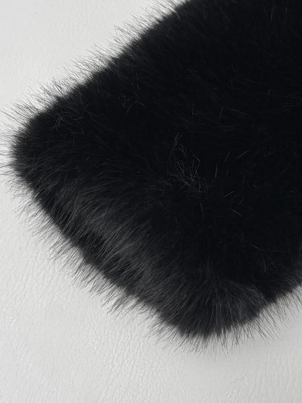 Corner of a black faux fur piece laid on a pale surface, showing the long glossy pile