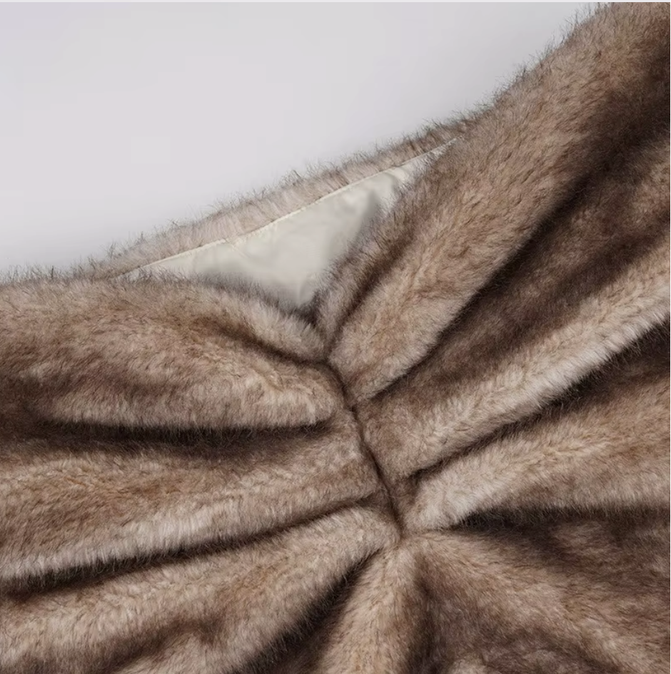 Close-up of gathered brown faux fur with the ivory satin lining showing at the waistband