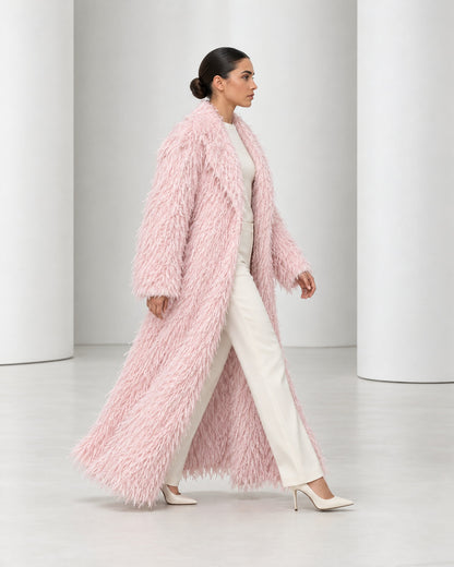 Side view of the Freja coat in blush mid-stride, worn open over ivory trousers