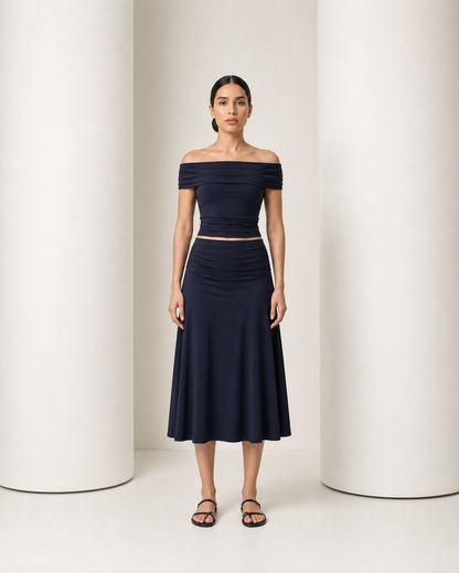 Model in the navy Hedda set, off-shoulder band top and high-waisted A-line midi skirt