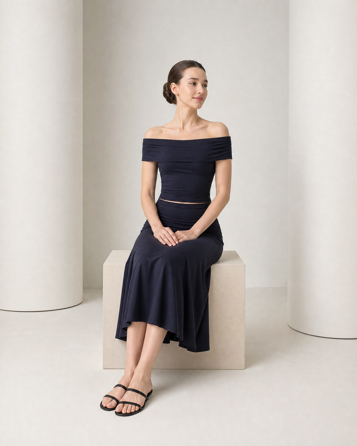 Model seated in the navy Hedda set, the ribbed skirt falling in soft folds over her knees