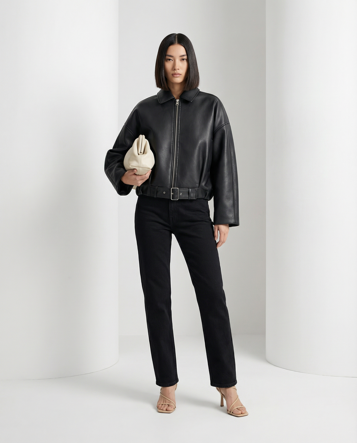 Black cropped leather jacket zipped to the belted waist, worn with straight black jeans