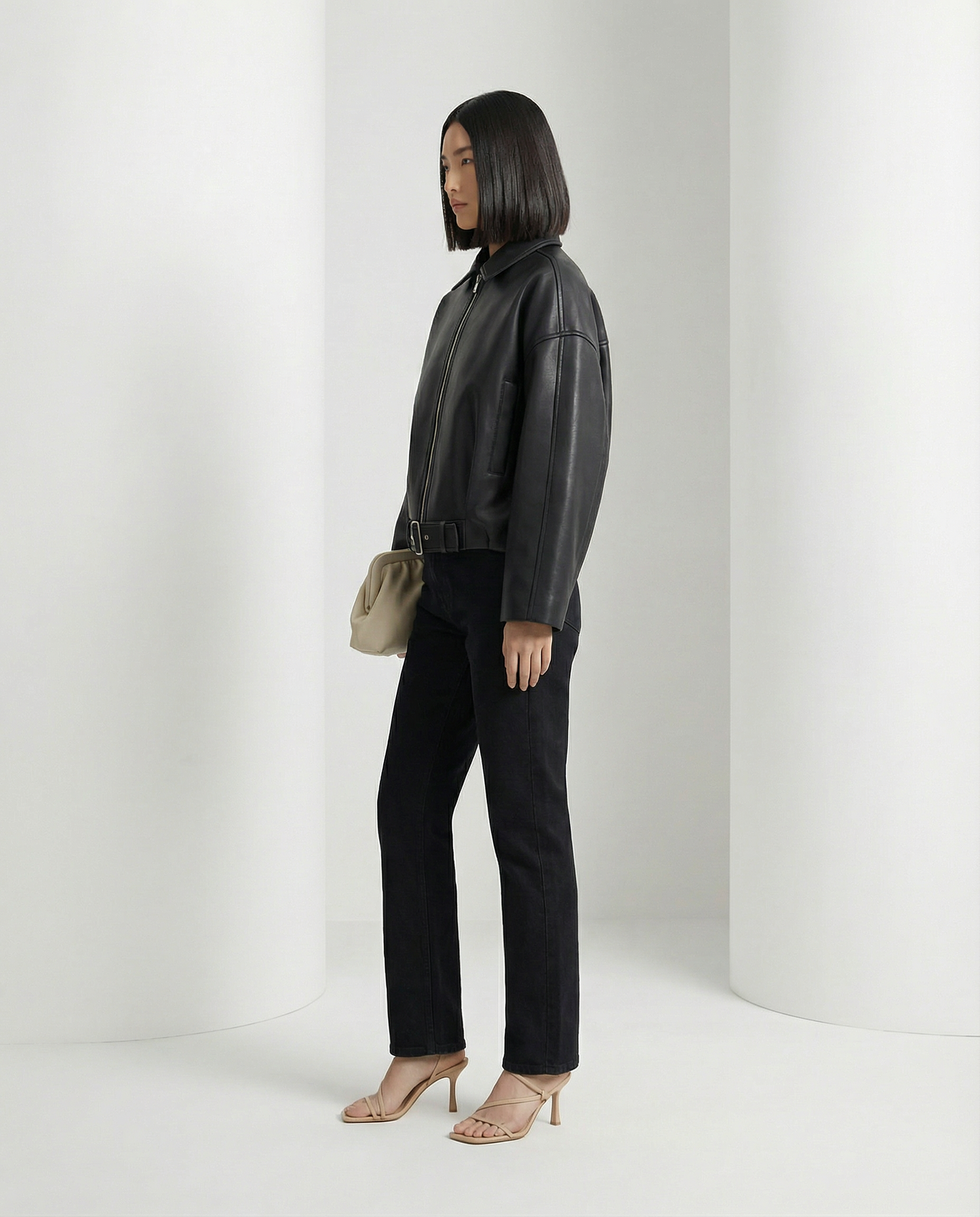 Three-quarter side view of the black cropped jacket showing the dropped sleeve and waist belt
