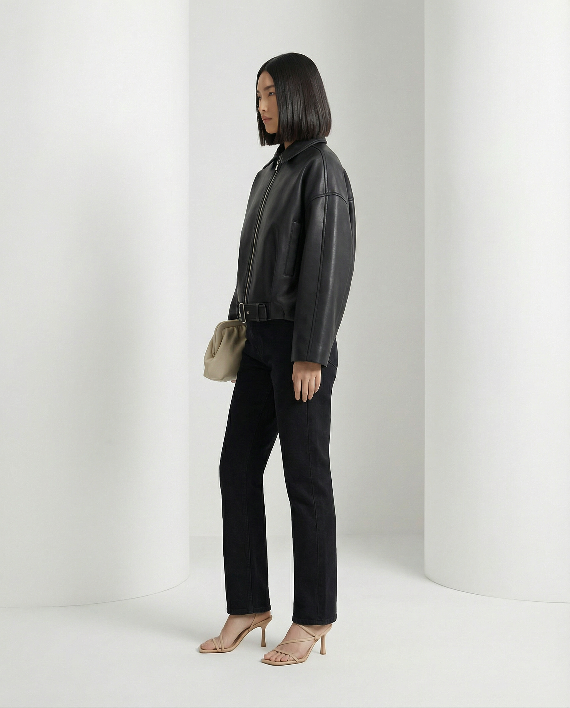 Three-quarter side view of the black cropped jacket showing the dropped sleeve and waist belt