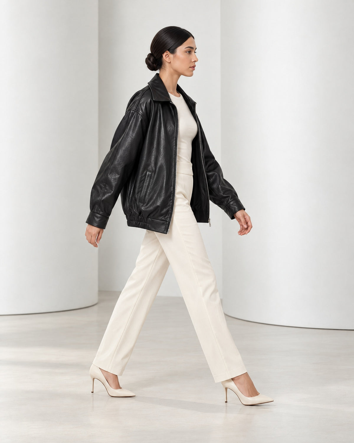 Side view of the Liv jacket in black mid-stride, showing its roomy oversized shape