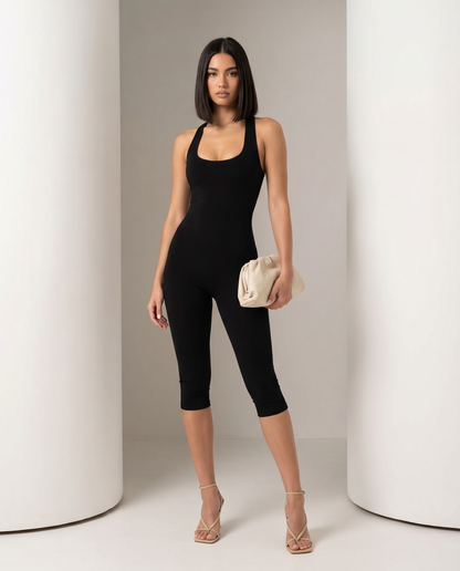 Cropped-leg black jumpsuit worn straight on to camera with strappy nude heels and a cream clutch