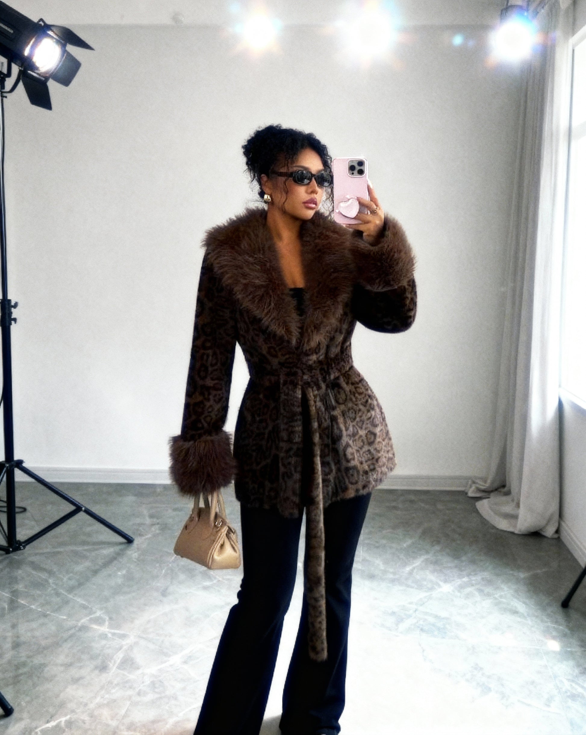 Cocoa leopard faux-fur coat belted, mirror selfie beside studio lights, three-quarter view