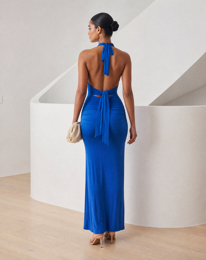 Cobalt blue halter maxi seen from behind with an open back and neck ties knotted at the shoulders