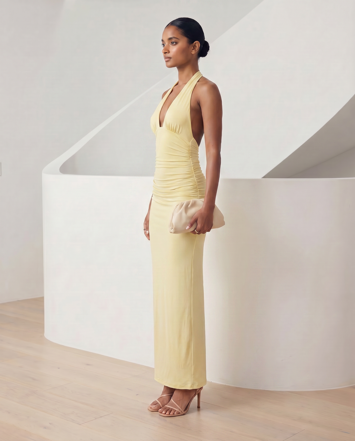 Meridiane halter maxi in light yellow, side profile showing the ruched hip and floor-skimming hem
