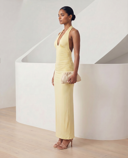 Meridiane halter maxi in light yellow, side profile showing the ruched hip and floor-skimming hem