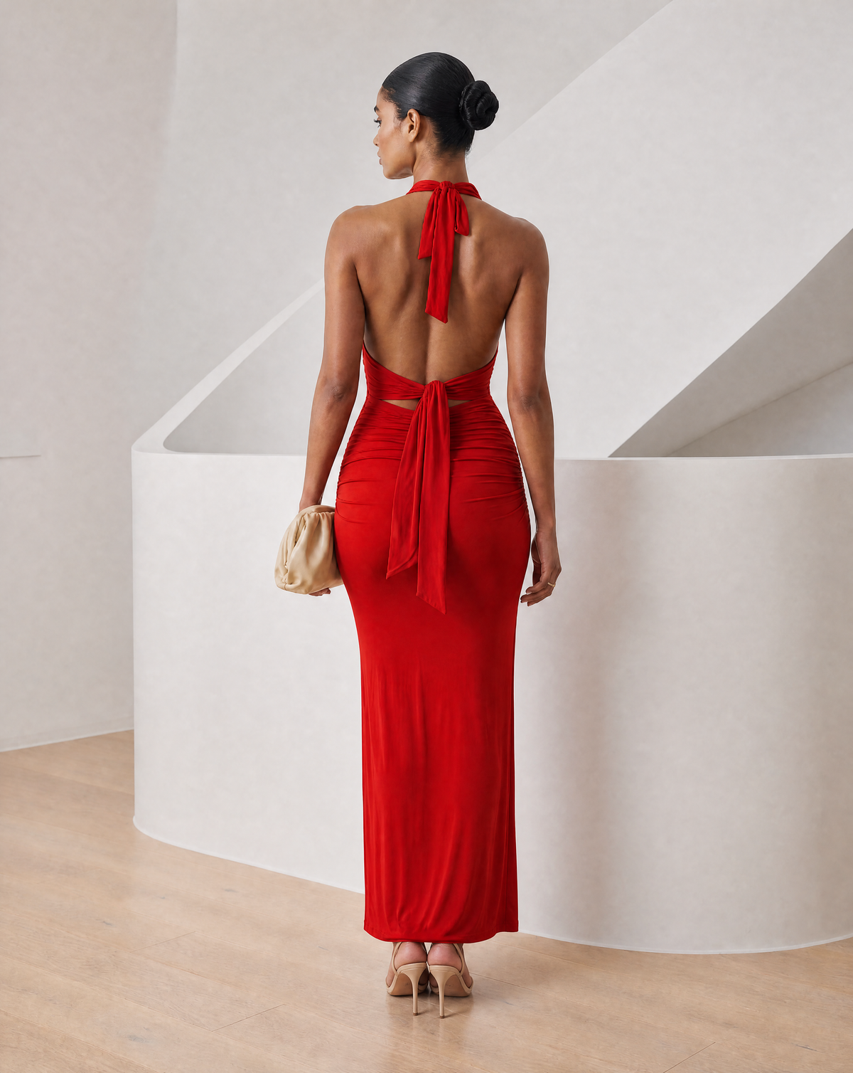 Red halter maxi from the back showing bare shoulders, tie sash and a long straight skirt