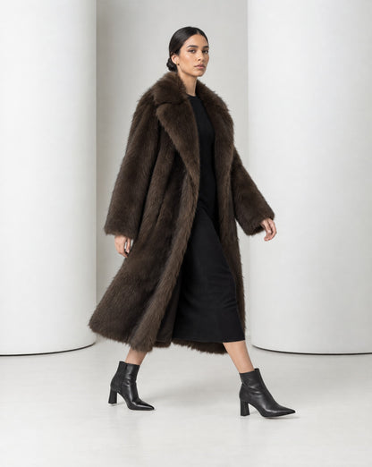 Side view of the Mirella bitter chocolate faux-fur coat mid-stride, the long open coat moving with the step