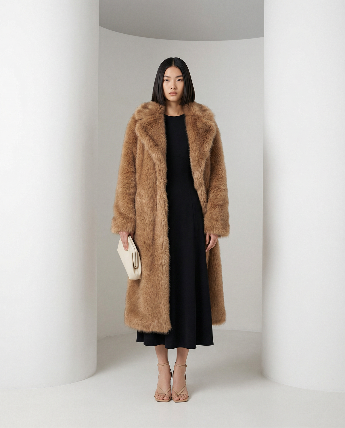 Mirella longline faux-fur coat in amber fox tan, front view with a cream clutch and bare ankles