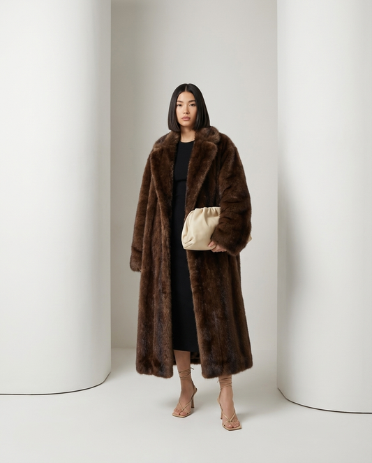 Mirella longline faux-fur coat in bitter chocolate, front view with a cream clutch held at the waist