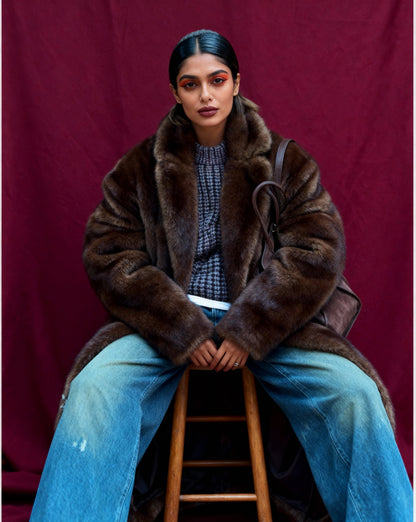 Bitter chocolate faux-fur coat worn open with a shoulder bag, seated straight-on with the collar standing up