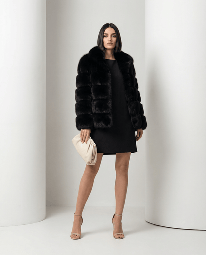 Black faux-fur bubble jacket worn open over a short black shift dress, full length with a cream clutch