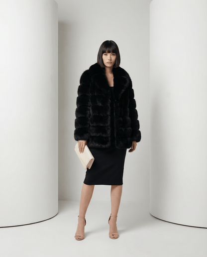 Black faux-fur bubble jacket with its shawl collar turned out, worn over a black midi dress
