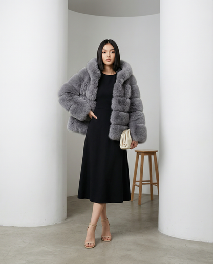 Grey Nova faux-fur bubble jacket with one hand in the pocket, worn over a black A-line midi dress