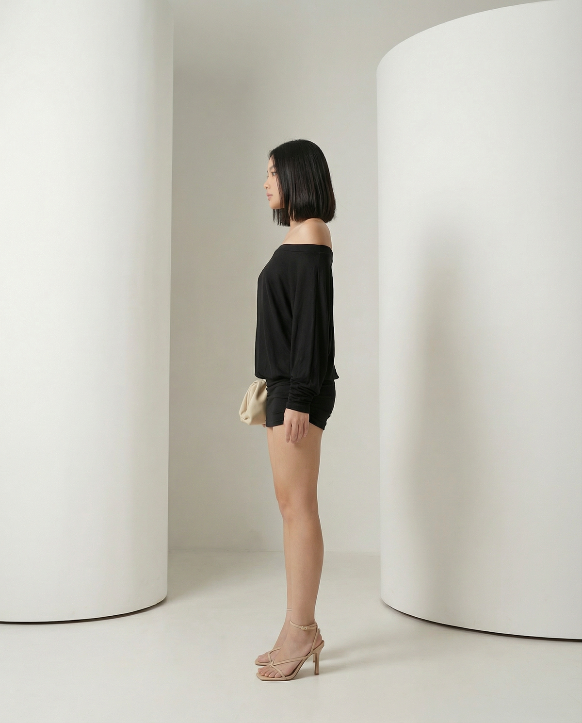 Side view of the black off-shoulder mini dress showing the bloused bodice and fitted skirt