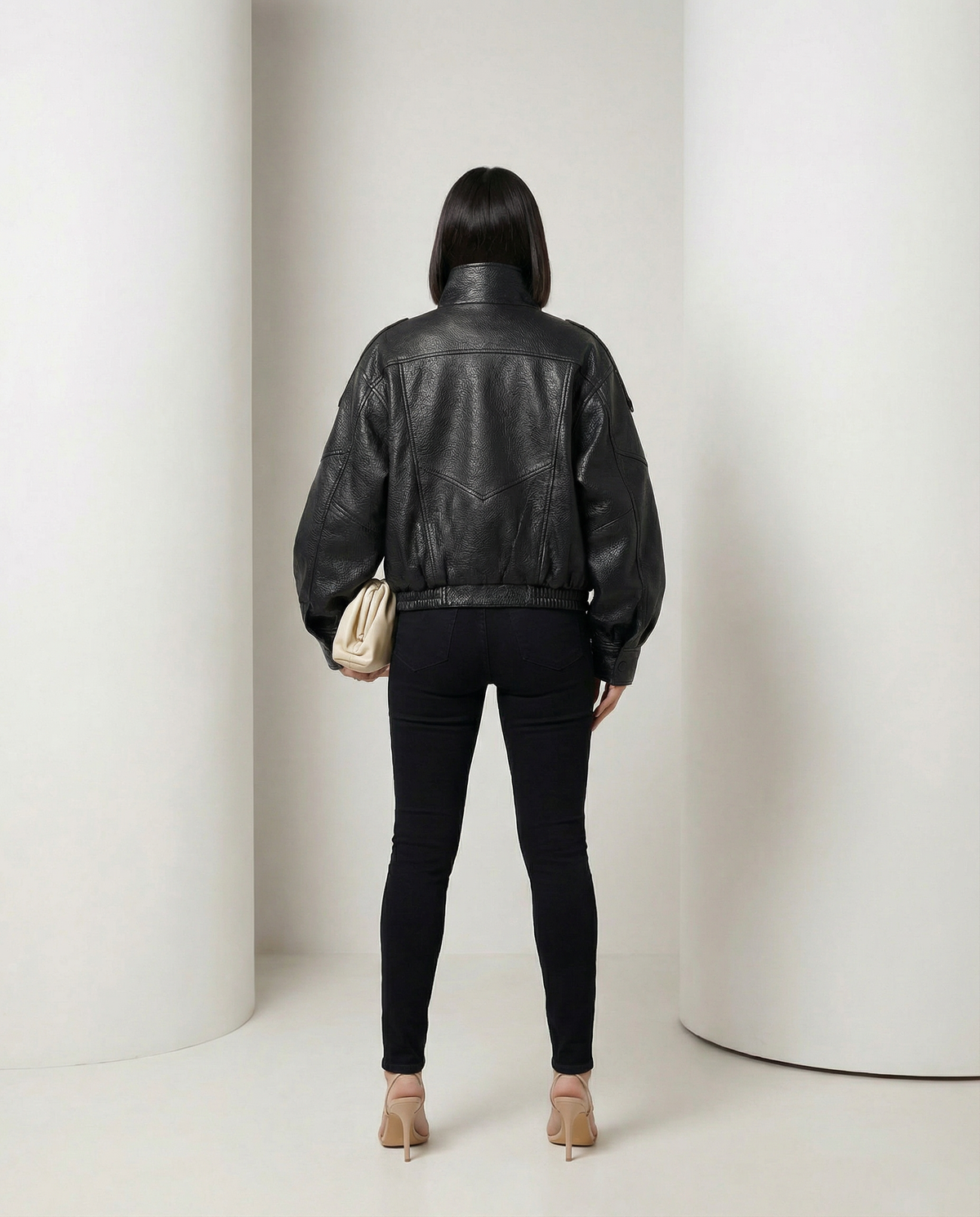 Black oversized leather-look bomber from behind, yoke seaming and banded hem, full length