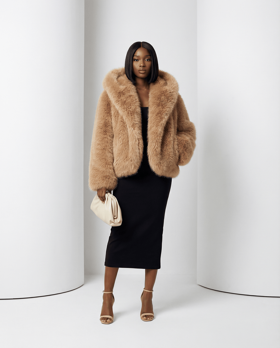 Amber fox Ravena hooded faux-fur jacket worn with the hood up over a black midi dress