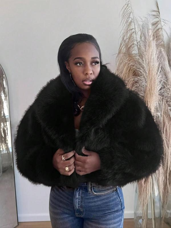 Cropped black faux fur jacket with an oversized collar worn over jeans beside pampas grass
