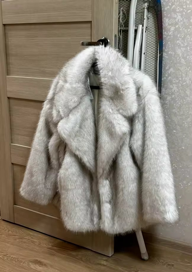 Pale grey faux-fur coat on a hanger against a light wooden door, collar and sleeves visible