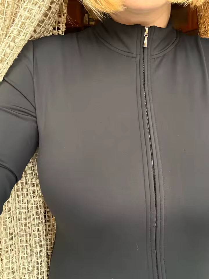 Close-up of a black jumpsuit's mock neck and full-length front zip in soft daylight